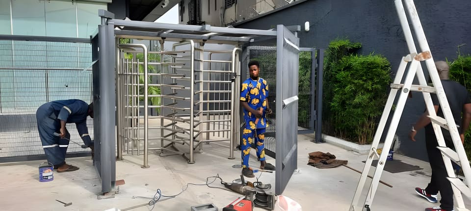 Technicians installing stainless-steel turnstiles and mesh partitions — Awolowo Road, Ikoyi, Lagos